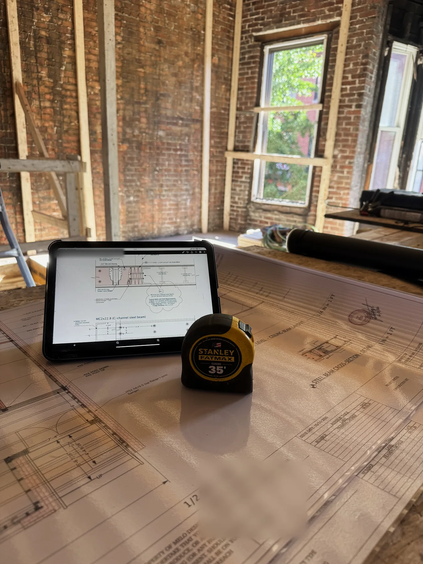 Structural drawings, a tablet and a tape measure on site in Charlestown