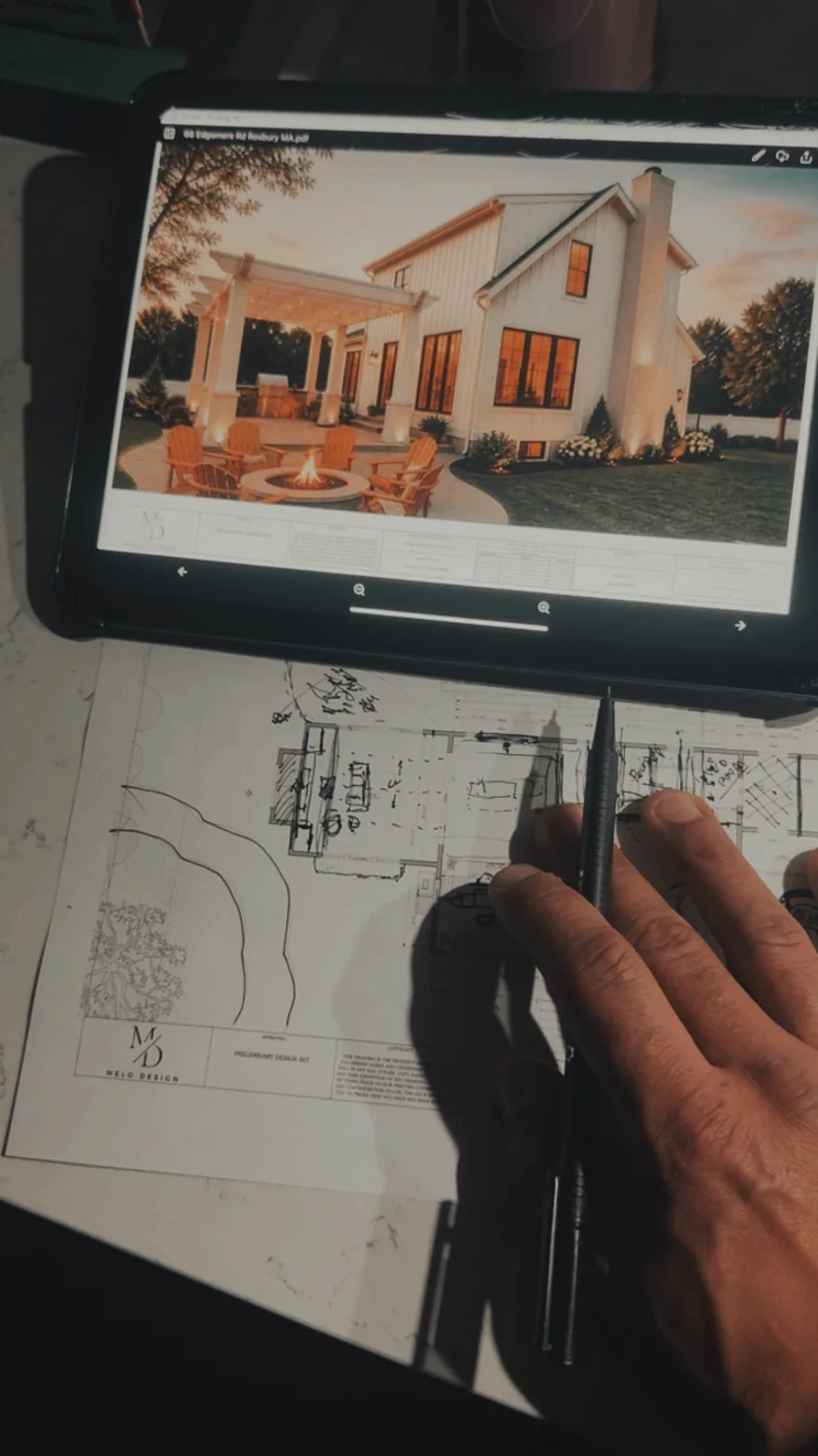 Hand sketching over a floor plan with a rendering open on a tablet
